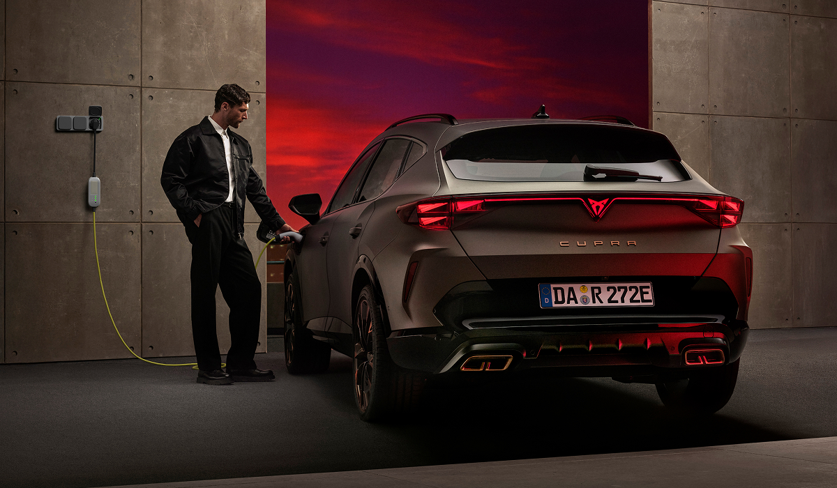 Frau lädt CUPRA Fahrzeug an einer Wallbox in einer beleuchteten Garage